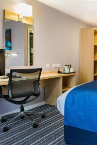 um quarto com uma cama e uma secretária com uma cadeira em Holiday Inn Express Manchester Airport, an IHG Hotel em Hale
