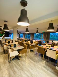 un restaurante con mesas, sillas y ventanas en Atoll Hotel Logis Angers, Beaucouzé en Beaucouzé