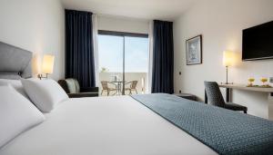 a hotel room with a bed and a table with chairs at Ilunion Calas de Conil in Conil de la Frontera