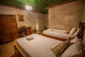 a room with two beds and a desk with a table at Hermes Cave Hotel in Uçhisar