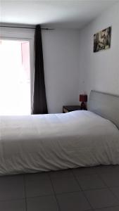 - une chambre avec un lit blanc et une fenêtre dans l'établissement Résid'Artel Cadarache - ITER, à Saint-Paul-lès-Durance