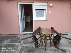 a table and chair sitting outside of a pink house at Apartman Pavle 2 in Virpazar