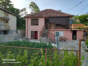 ein rosa Haus mit einem Zaun davor in der Unterkunft Apartman Pavle 2 in Virpazar