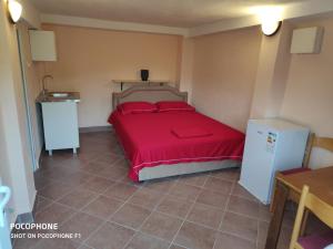 a bedroom with a bed with red sheets and a refrigerator at Apartman Pavle 2 in Virpazar