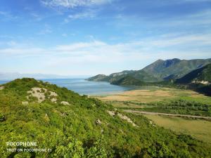 a view of a hill with the ocean and mountains at Apartman Pavle 2 in Virpazar +1 photo