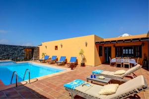 een villa met een zwembad en een patio bij CASA ACEQUIA in Tinajo