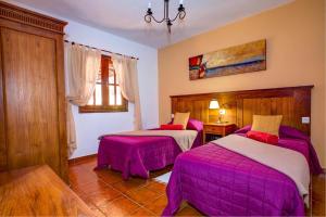 een slaapkamer met 2 bedden met roze dekens bij CASA ACEQUIA in Tinajo