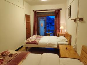 ein Hotelzimmer mit 2 Betten und einem Tisch in der Unterkunft 多依湾客栈Havre de paix DuoYiWan in Kreis Yuanyang