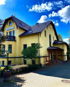 ein großes gelbes Gebäude mit schwarzem Dach in der Unterkunft Hotel Am Park in Pasewalk