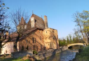 an old building next to a river with a bridge at Château de la Venerie in Denicé