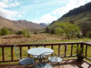 a table and chairs on a deck with mountains at Rocky Mountain View Cottage in Killilan +7 photos