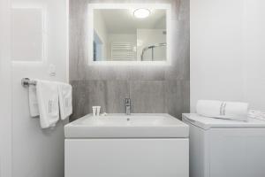 biała łazienka z umywalką i lustrem w obiekcie Apartos Sailor - Luxury Apartments w mieście Ustronie Morskie