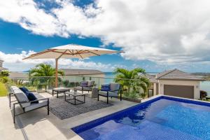 un patio con sombrilla y piscina en Tigers Eye Condo Grenada en Egmont