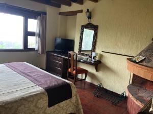 a bedroom with a bed and a desk and a mirror at Villa San Jose Hotel & Suites in Morelia