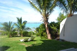 Deux chaises blanches assises sur l'herbe près de l'océan dans l'établissement Villa du Lagon, à Blue Bay