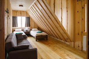 Habitación con 2 camas y sofá en una habitación con paredes de madera. en Rosi Puhkemaja en Koljala