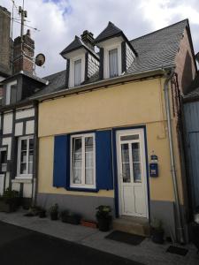 una casa amarilla y azul con una puerta blanca en L'Estacade : maison de pecheur, en Saint-Valery-sur-Somme