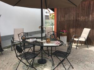 una mesa con sillas y una sombrilla en el patio en B&B Gira-Sole, en Cuneo