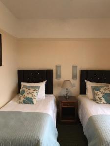 a hotel room with two beds and a table with a lamp at The Aldwick in Bognor Regis