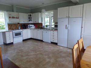 una cocina con armarios y electrodomésticos blancos y una mesa en Villa Freja, en Linköping