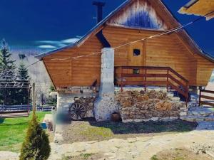 a large wooden cabin with a stone wall at Kanjon Uvac in Sjenica