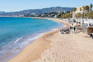 a beach with people sitting on chairs on the sand at Near Croisette- 4 Star Studio -SeaView in Cannes
