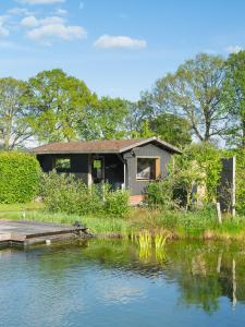 a house with a dock next to a body of water at B&B Pipowagen "de Luxe" op Wellness Camping en B&B in Winterswijk-Meddo
