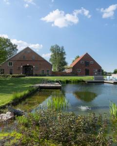 a large pond in front of a brick building at B&B Pipowagen "de Luxe" op Wellness Camping en B&B in Winterswijk-Meddo