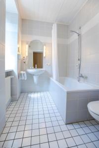 Baño blanco con bañera y lavamanos en Hajo´s Germania Lodge & Irish Pub en Rüdesheim am Rhein