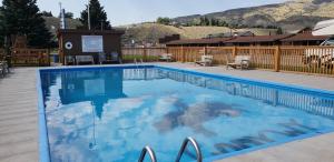 a swimming pool at a resort with mountains in the background at Big Bear Motel in Cody