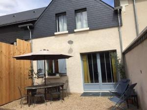 un patio con una mesa y una sombrilla frente a una casa en le gite de Jules en Azay-le-Rideau