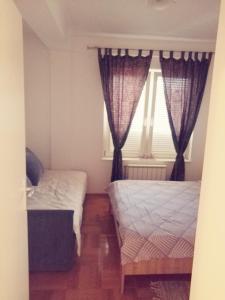 a small bedroom with two beds and a window at Spa apartman Iva in Banja Luka