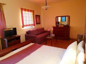 um quarto com uma cama, um sofá e uma televisão em Elaianthos em Kalamata