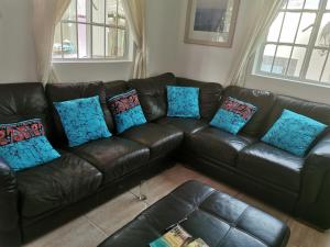 a black leather couch with blue pillows in a living room at Mandinka Lodge in Kololi