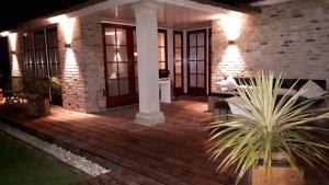 un porche con una terraza de madera por la noche con luces en Villa Pura Vida en Oud-Ade