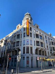 a white building with a flag on top of it at SUITES CASA LUBÉN in León