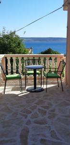 - 2 chaises et une table sur une terrasse donnant sur l'océan dans l'établissement Apartment Ante and Dijana, à Starigrad-Paklenica