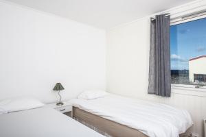 a white bedroom with two beds and a window at Apt 201 - Andenes Whale Safari Apartments in Andenes