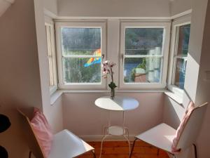a small table and two chairs in a room with two windows at Cafe-Konditorei-Pension Sander in Niederfell
