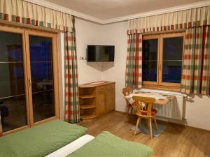 een kamer met een bed, een tafel en een televisie bij Brandnerhof in Bad Hofgastein