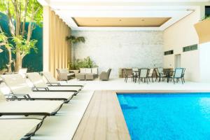 a pool with chaise lounge chairs and a swimming pool at Palmarena Rooms & Residences - Long Stay Comfort with Parking, Sauna, Gym & Pool - Steps from 5th Avenue in Playa del Carmen