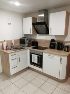 La cuisine est équipée de placards blancs et d'un four avec plaques de cuisson. dans l'établissement Ferienapartment "Vier Pfoten" in Korbach, à Korbach