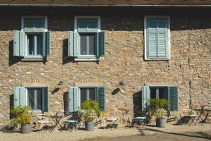 un edificio de piedra con persianas azules, mesas y sillas en Vánkos Bed & Bistro en Badacsonyörs