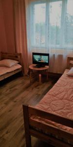 a room with two beds and a desk with a television at Gospodarstwo u Krakusa in Doboszowice
