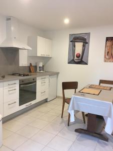 uma cozinha com armários brancos e uma mesa e uma mesa e uma cadeira em Le bord de Loire em Basse-Indre