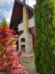 a house with a brick fireplace and a large green bush at Apartments Hill House Zlatibor in Zlatibor