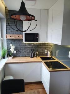 a kitchen with white cabinets and a black microwave at Iława Apartamenty in Iława