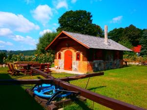辛巴克的住宿－Pensjonat Kupperówka- Stadnina Koni Kolano，一座带红色门和野餐桌的小建筑