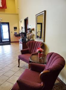 a room with two chairs and a table and a mirror at The Edgewood Hotel and Suites in Fairbury