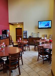 un restaurante con mesas y sillas y TV de pantalla plana en The Edgewood Hotel and Suites en Fairbury